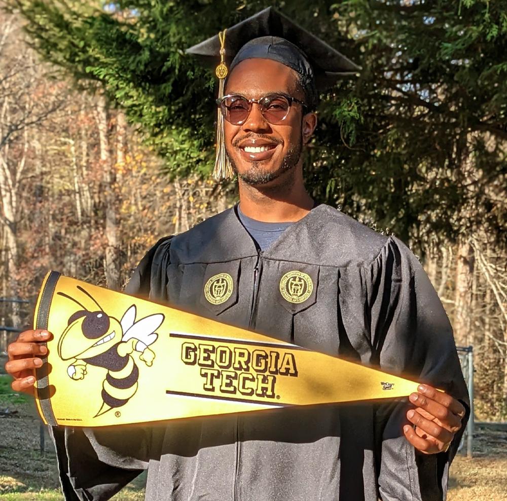 John Respert in cap and gown holding a Georgia Tech pennant