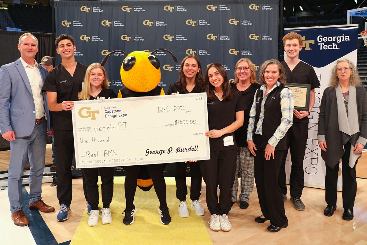 group of students and faculty holding check with mascot Buzz