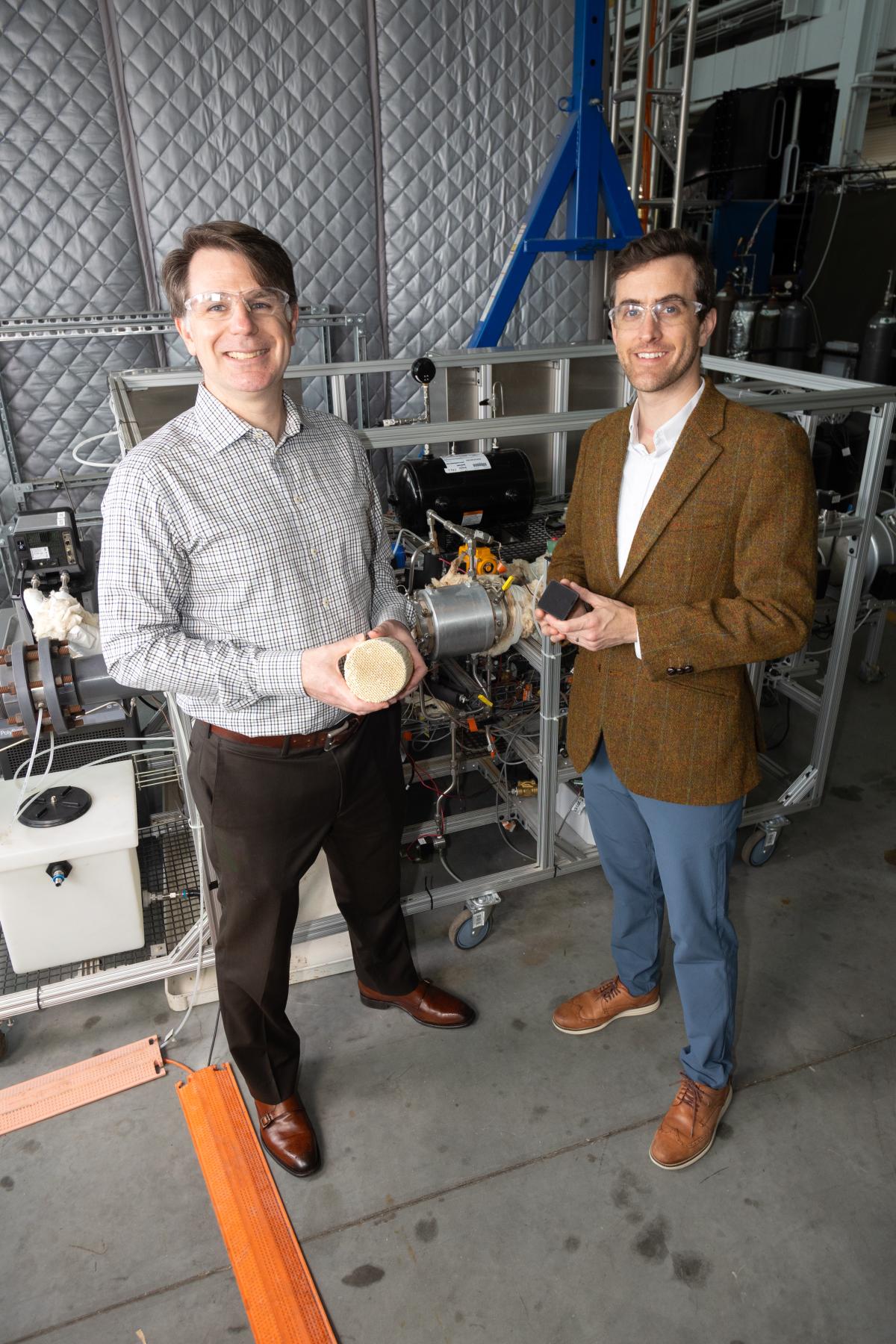 two people holding components stand in front of a direct air capture system