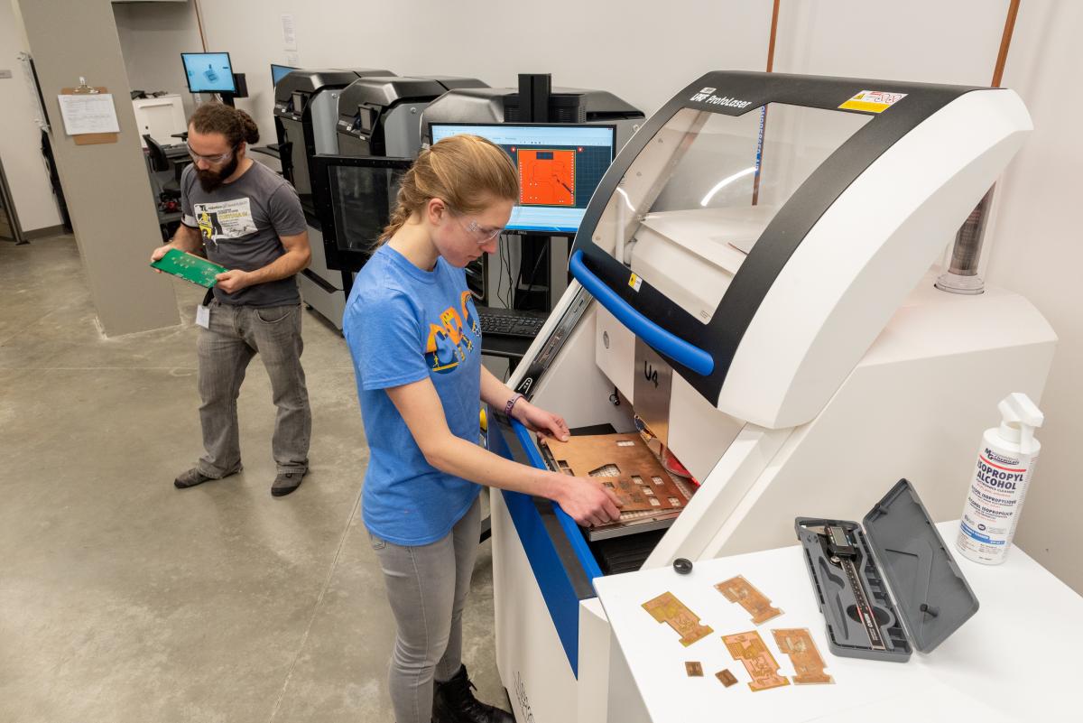 Two students working in the IDC using a 3D printer