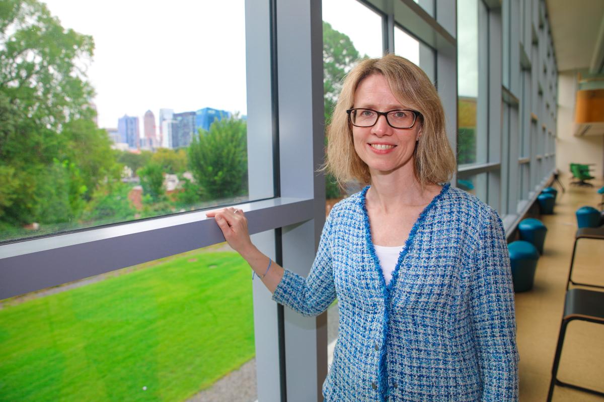 Martha Grover standing at a wall of windows in the library