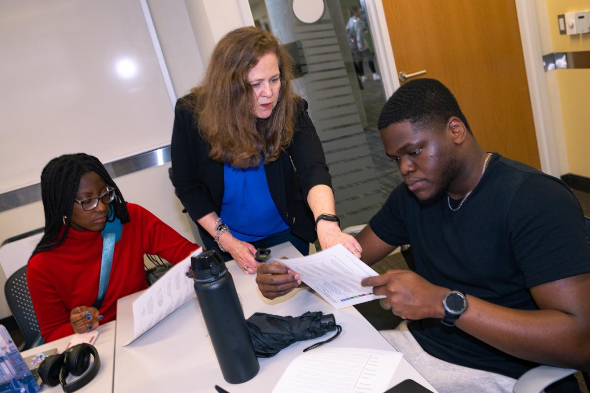 Mary Lynn Realff works with two students at a classroom table