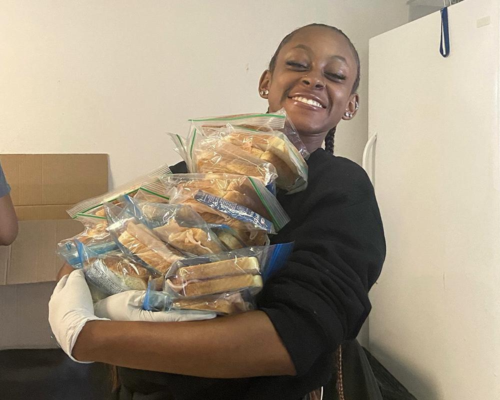 Jordine Jones with an armful of sandwiches in resealable bags.