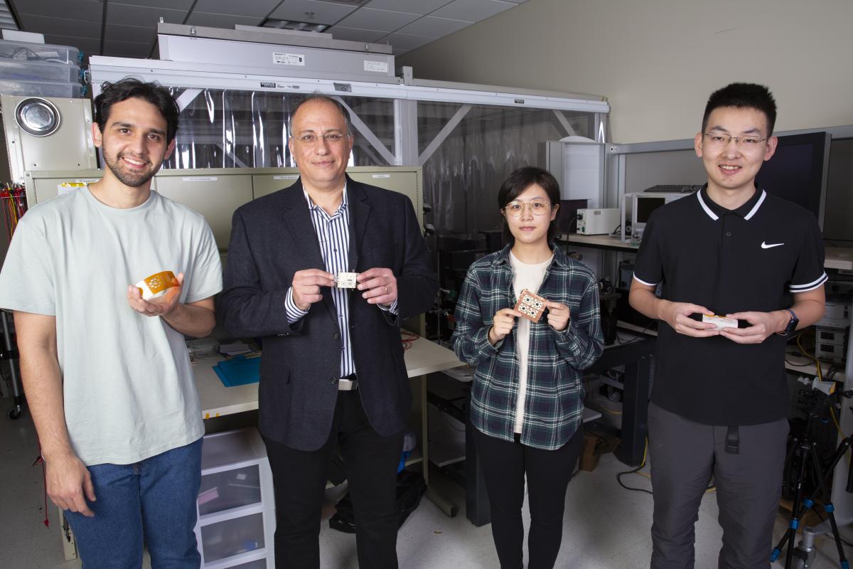 ECE Professor Manos Tentzeris and three students hold up 5G transmitters in the lab