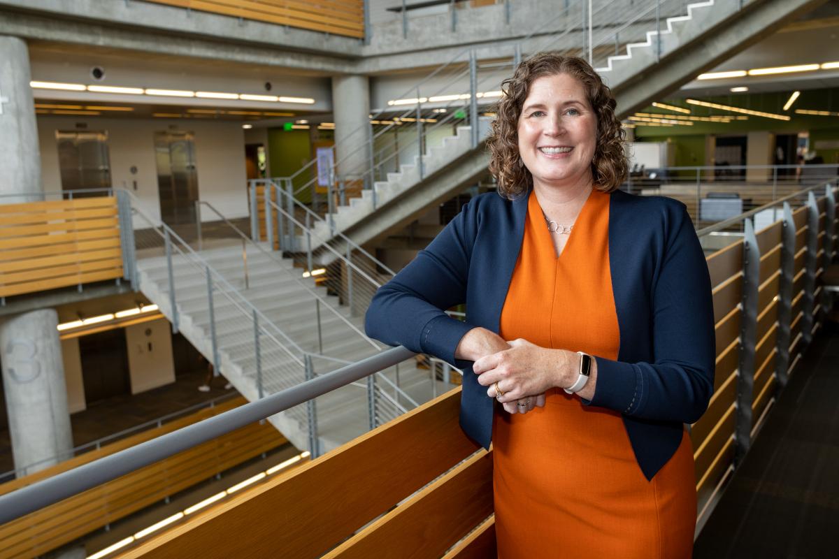 Karen Feigh stands at a railing in Clough Commons with a staircase in the background