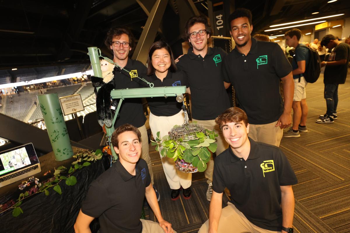 group of students surrounding a bucket of food hanging from a pole