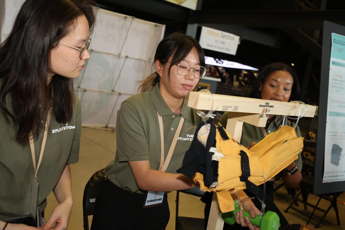 three female students working with a splint suspended on a device