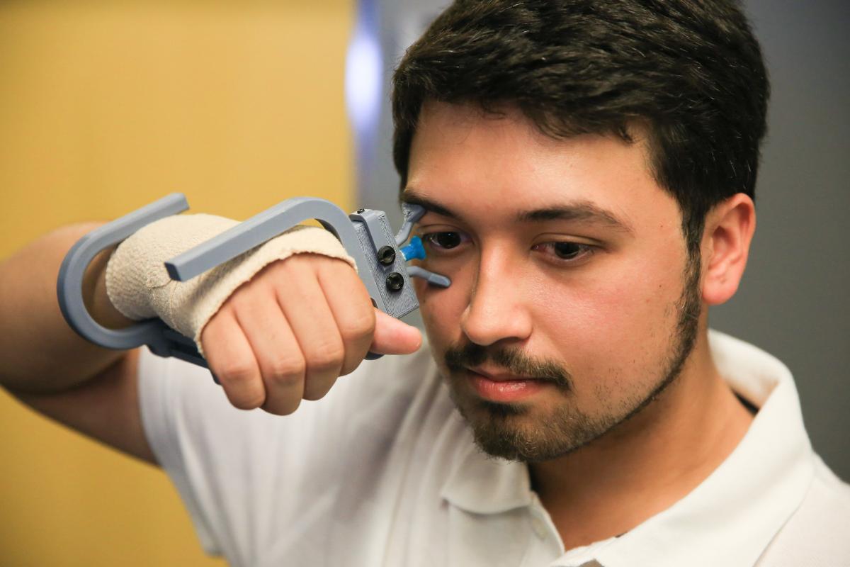 man wearing wrist-mounted device touching eye