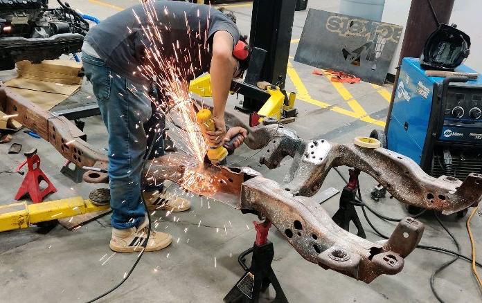 Alex Castrejon works on the frame of the Wreck Racing car