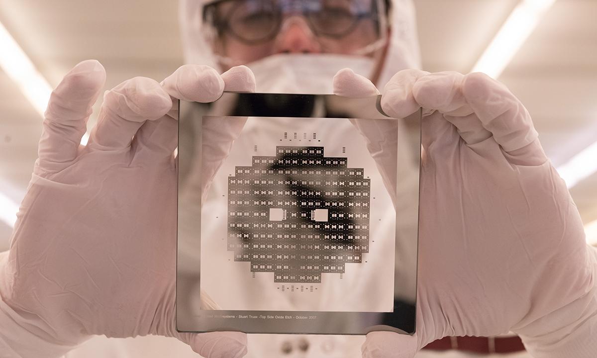 Devin Brown holds a silicon wafer in the Marcus Nanotechnology Building clean room.