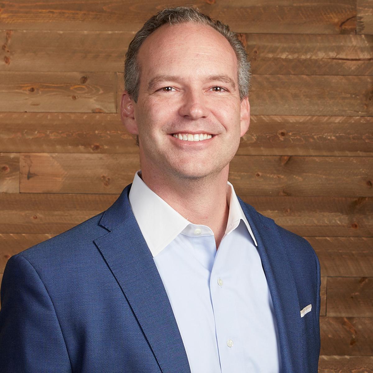 James Rains standing in front of brown background 