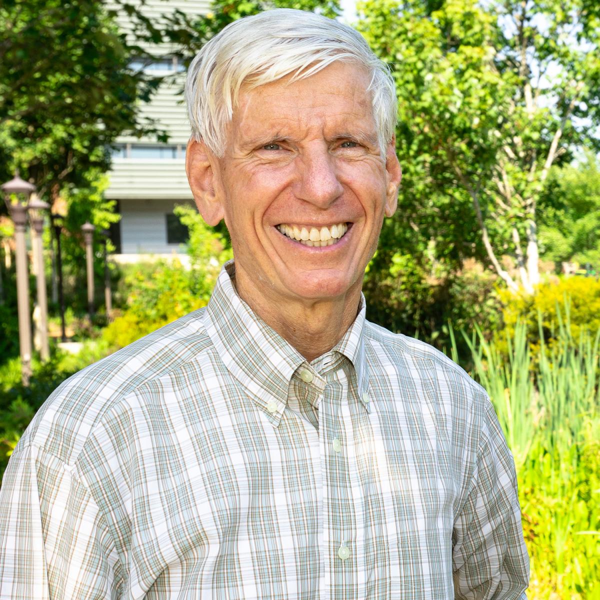 Paul Kohl headshot, standing outside in front of plants