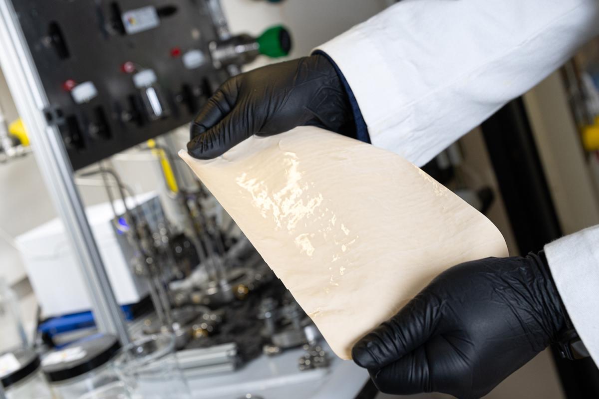 Two hands holding an example of the DUCKY polymer membranes researchers created to perform the initial separation of crude oils with significantly less energy. (Photo: Candler Hobbs)