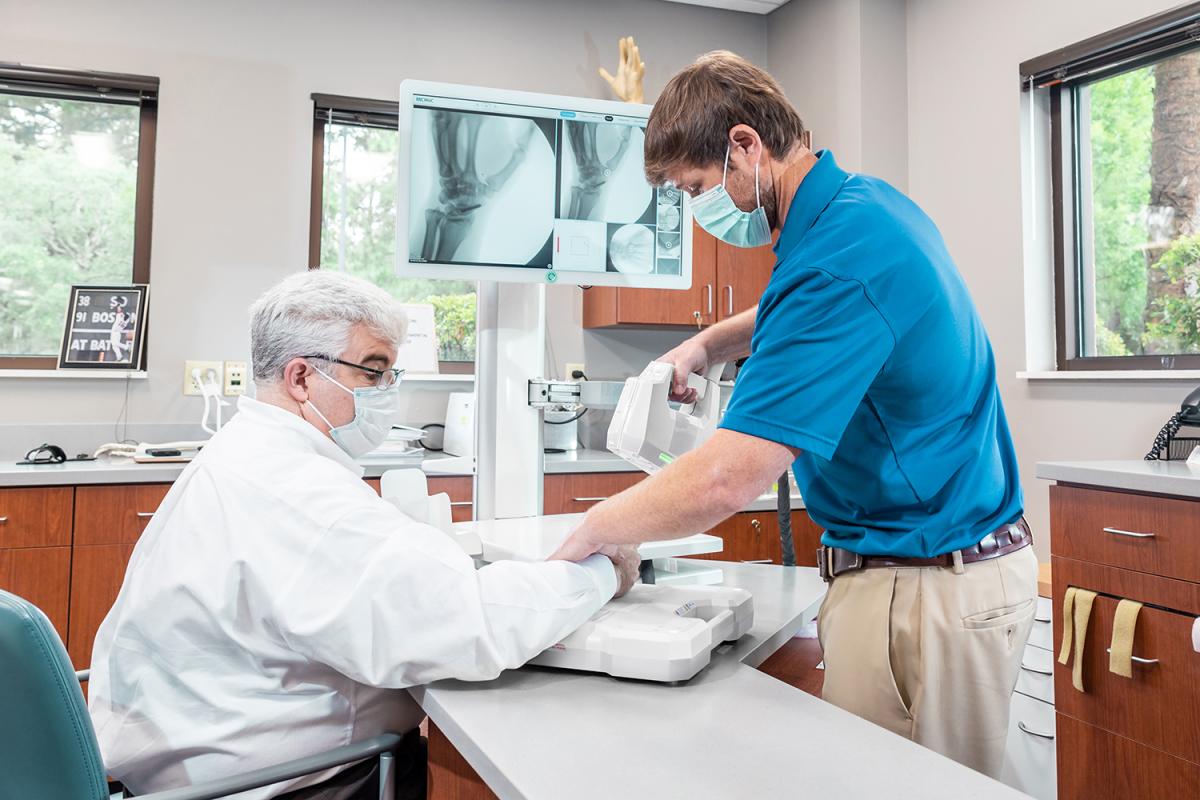 A person uses the OXOS portable X-ray device to take an image of another person's hand