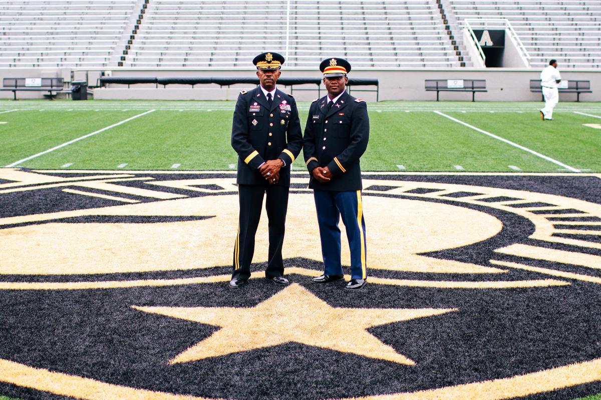 Ronald Johnson and Ahmad Bradshaw standing on the Army logo at midfield in dress uniform.