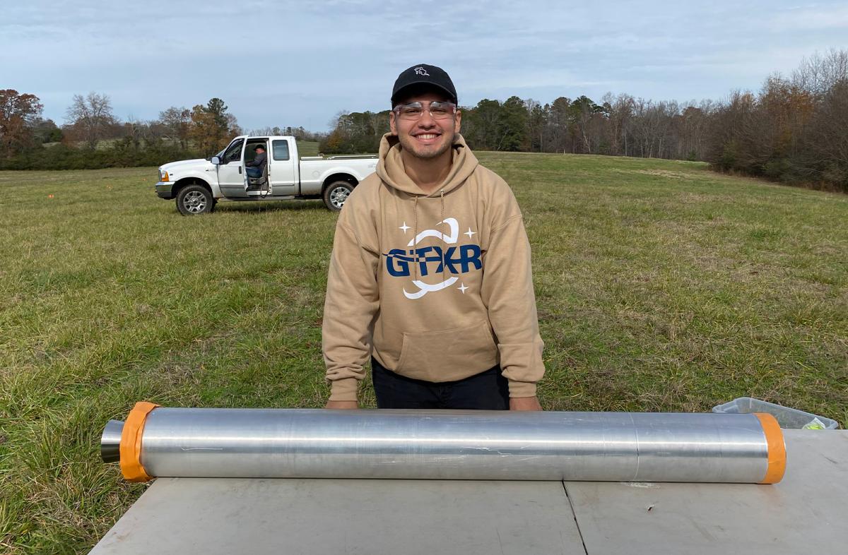 Kian Zarbaf in a field with a rocket component