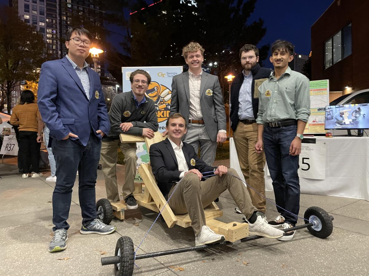 team of students surrounding a go-kart, in front of the atlanta skyline