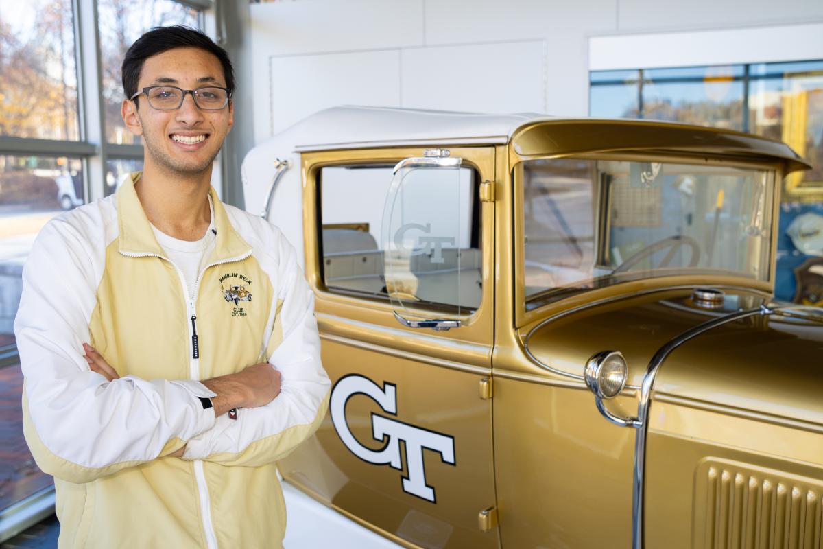 2023 driver Omar Khan stands next to ramblin wreck 