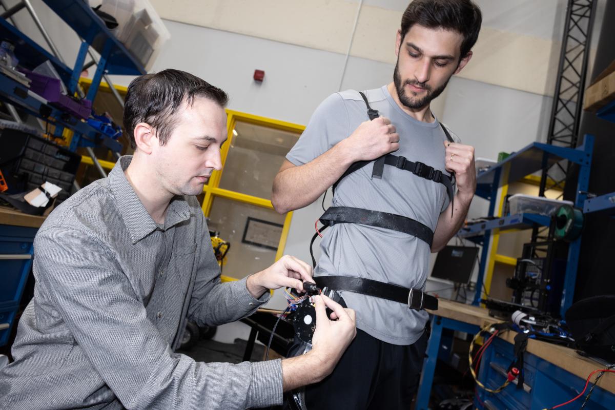 member of team assisting another member putting on exoskeleton