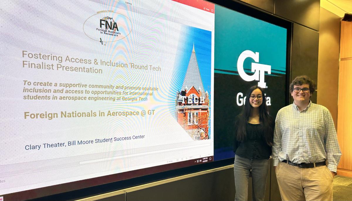 Two members of the winning FAIR Tech competition team, Jasrayman “Ray” Thind and Alfonso Lagares de Toledo, stand at a screen displaying the title slide of their final presentation.