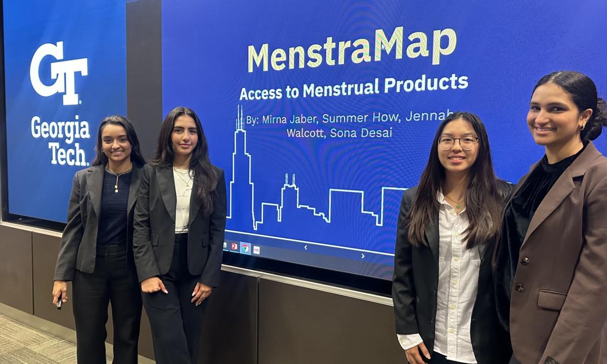 The MentraMap team standing next to a screen with the title slide from their final presentation in the FAIR Tech competition.