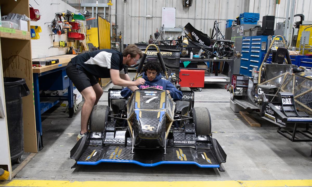 A Summer Engineering Institute camper sits in the GT Motorsports Formula SAE car while a member of the team leans over and tells them about the vehicle. (Photo: Liz Kelly)