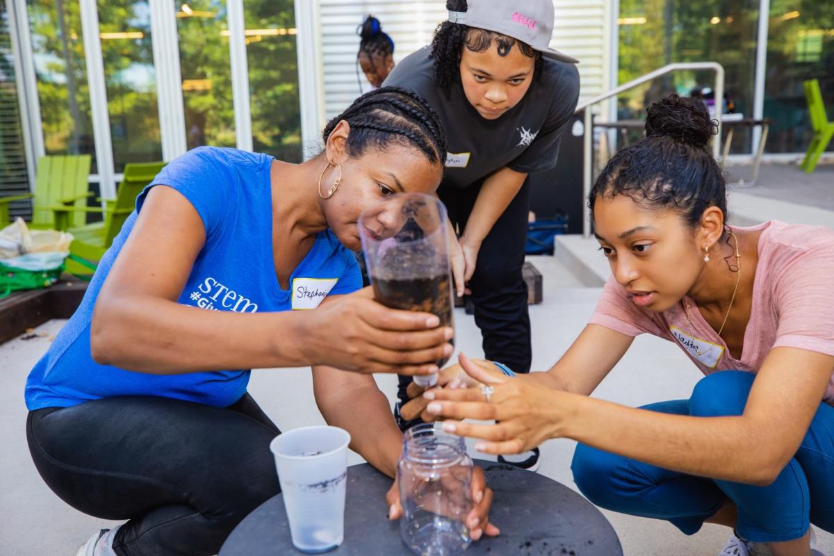 Three people pour into water filtration system