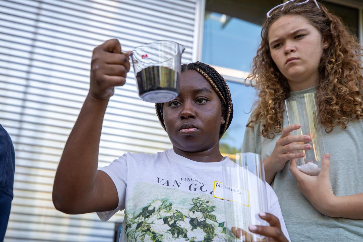 two girls look at soil in a cup