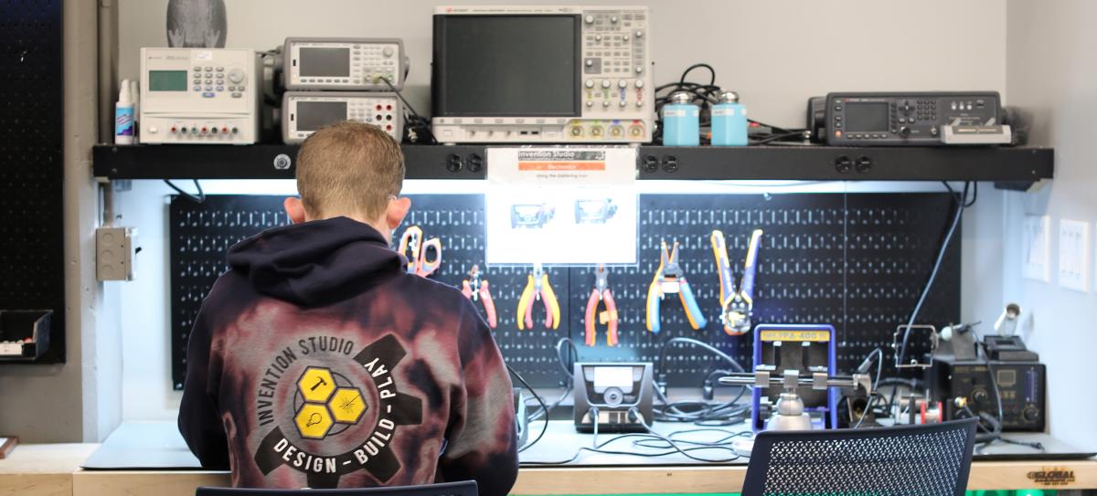 A student at a workbench with tools in the Flowers Invention Studio.