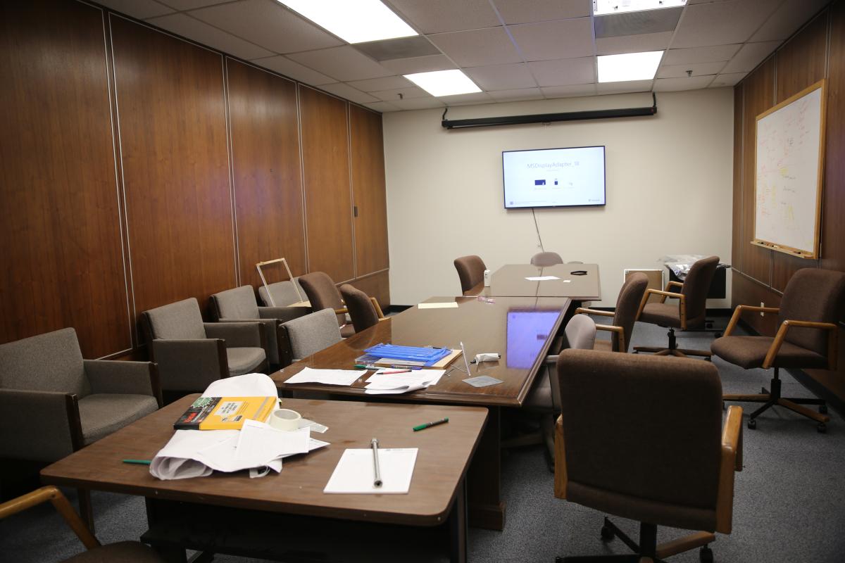 A dated conference room with wood paneling and old padded chairs