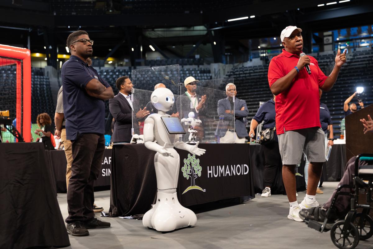 Calvin Mackie speaks next to a robot