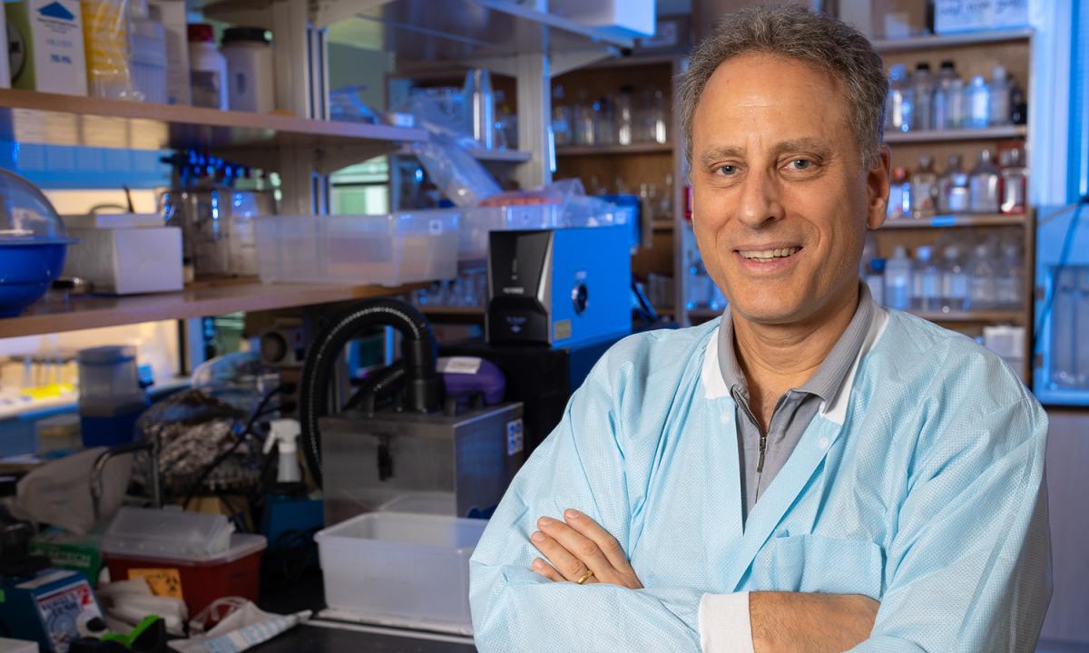 Mark Prausnitz poses with arms crossed in his lab with shelves of materials and bottles in the background.