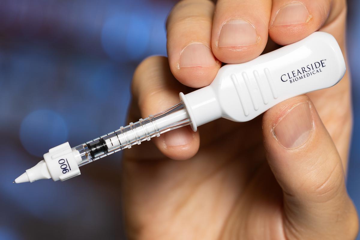 A hand holding a white injection device with a 1 mm microneedle at the tip.