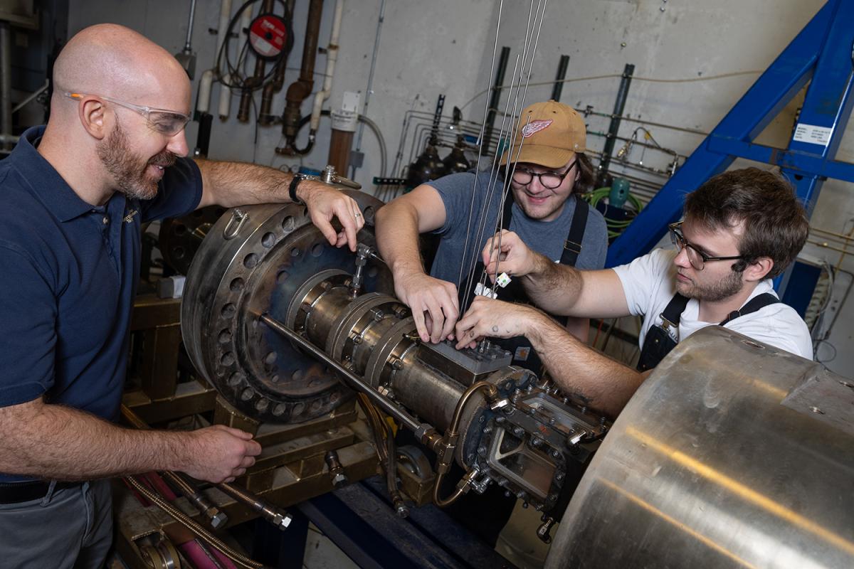 Three people work in a combustion lab