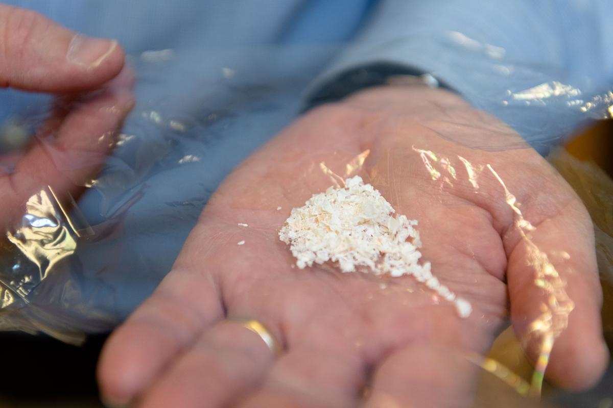 a closeup of a hand holding a plastic-like material with crumbs in the middle