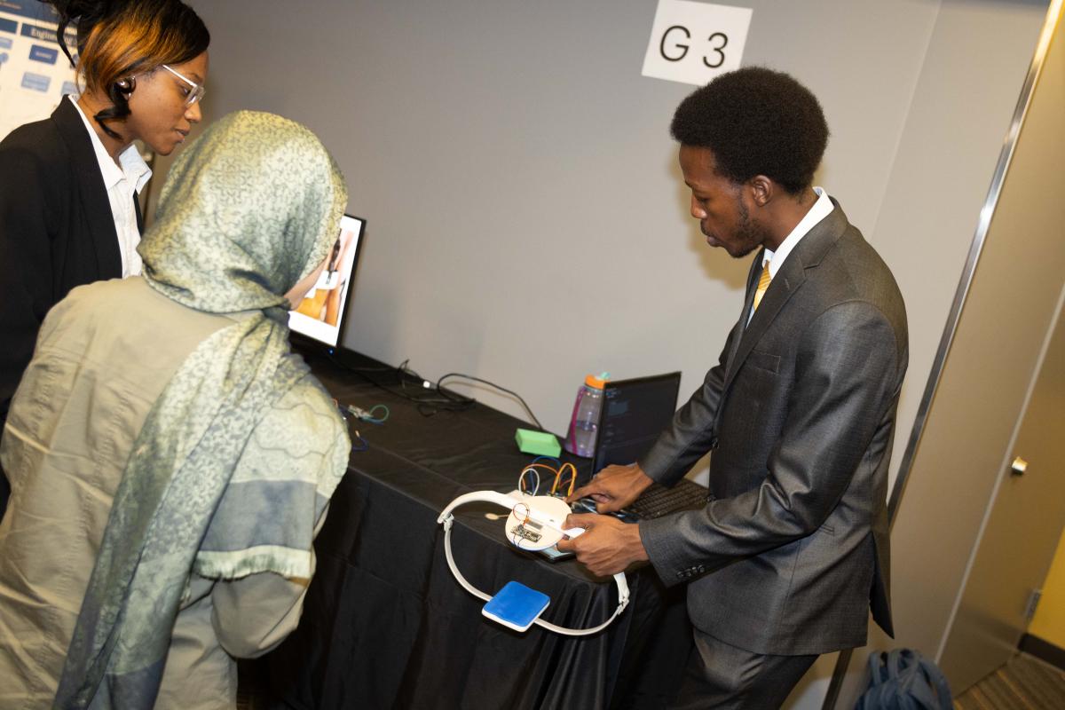 a student shows two people a circular device on a table 