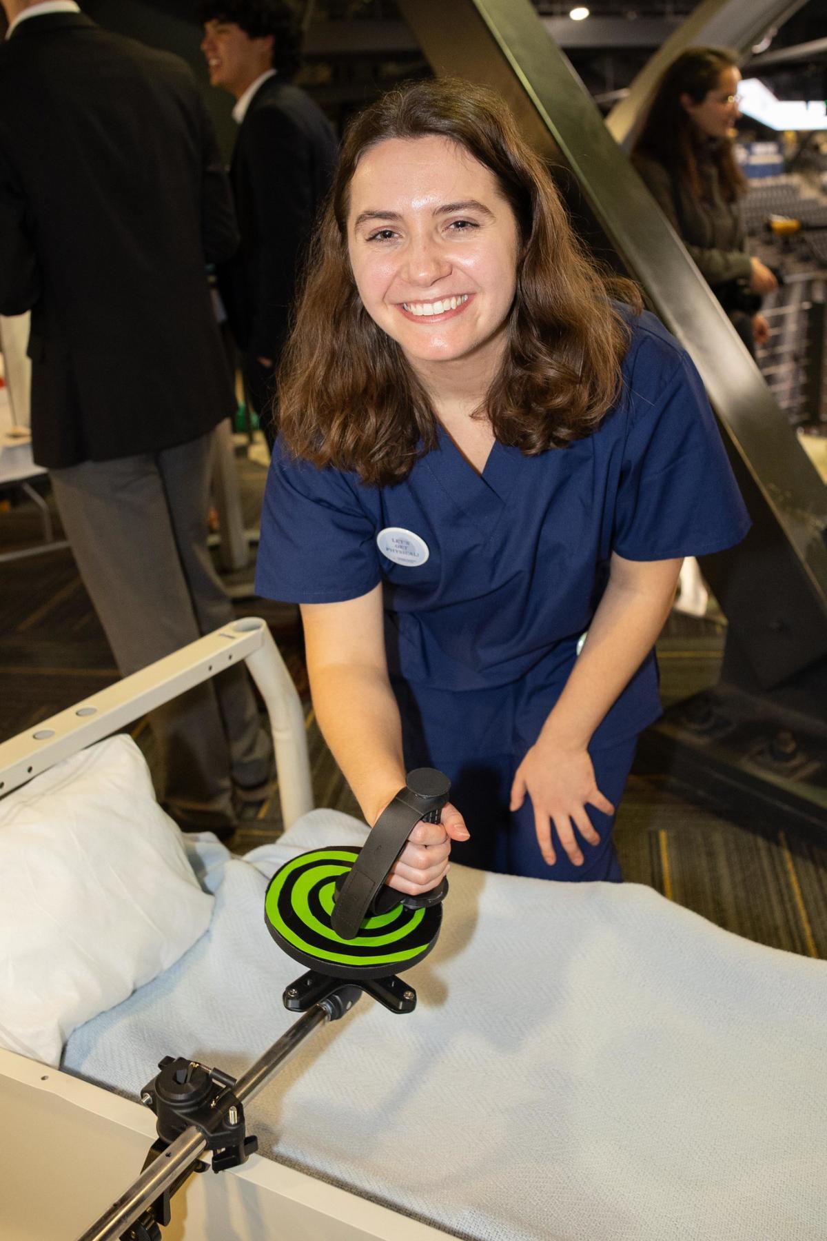 female student in dark blue holds a clamp device across a bed