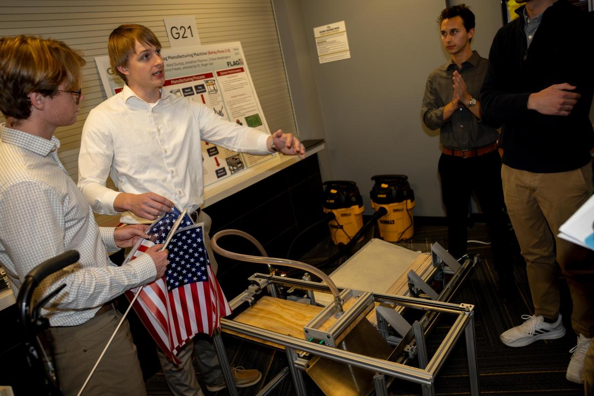 two students holding American flags show other people their device