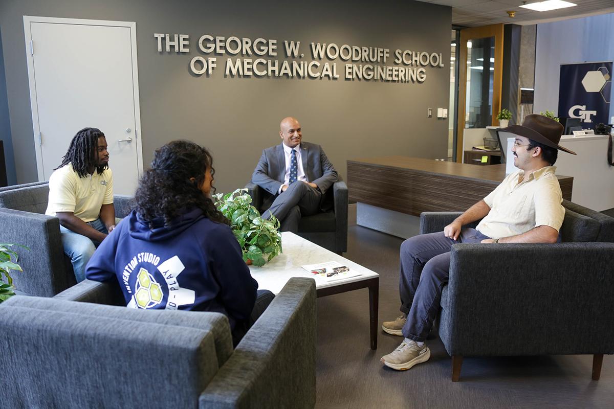 Devesh Ranjan and three students sit under a "Woodruff School" sign