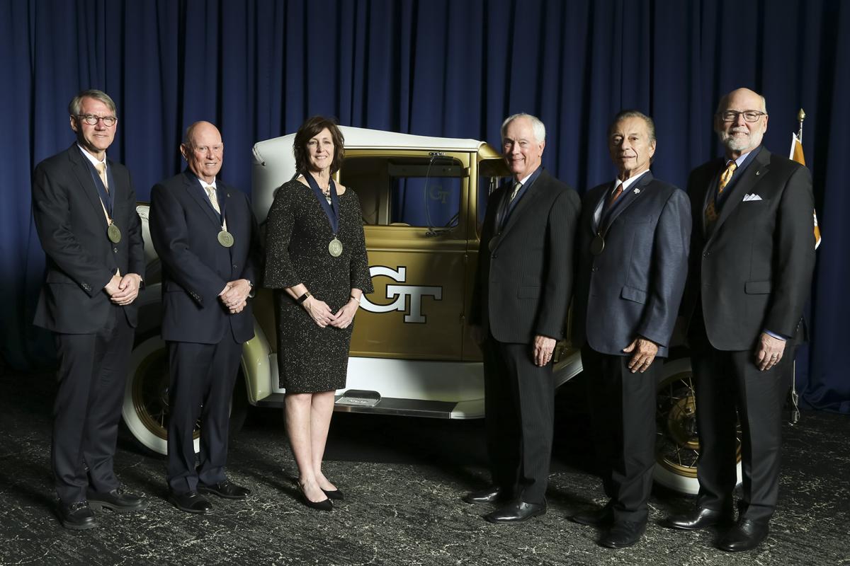 Six Hall of Fame inductees stand with the Ramblin' Wreck against a blue backdrop at the College of Engineering Alumni Awards and Induction Ceremony.