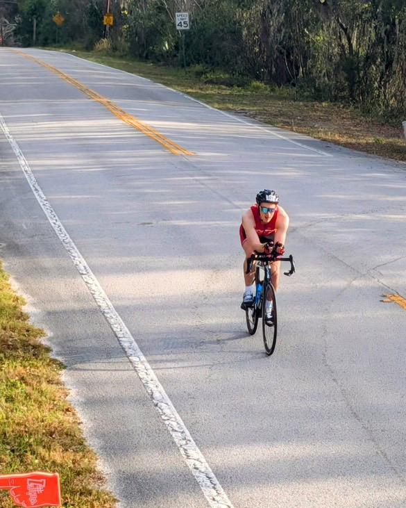 Jacob Beldick riding his bike on a two-lane road during the cycling portion of the Ultraman Florida triathlon.