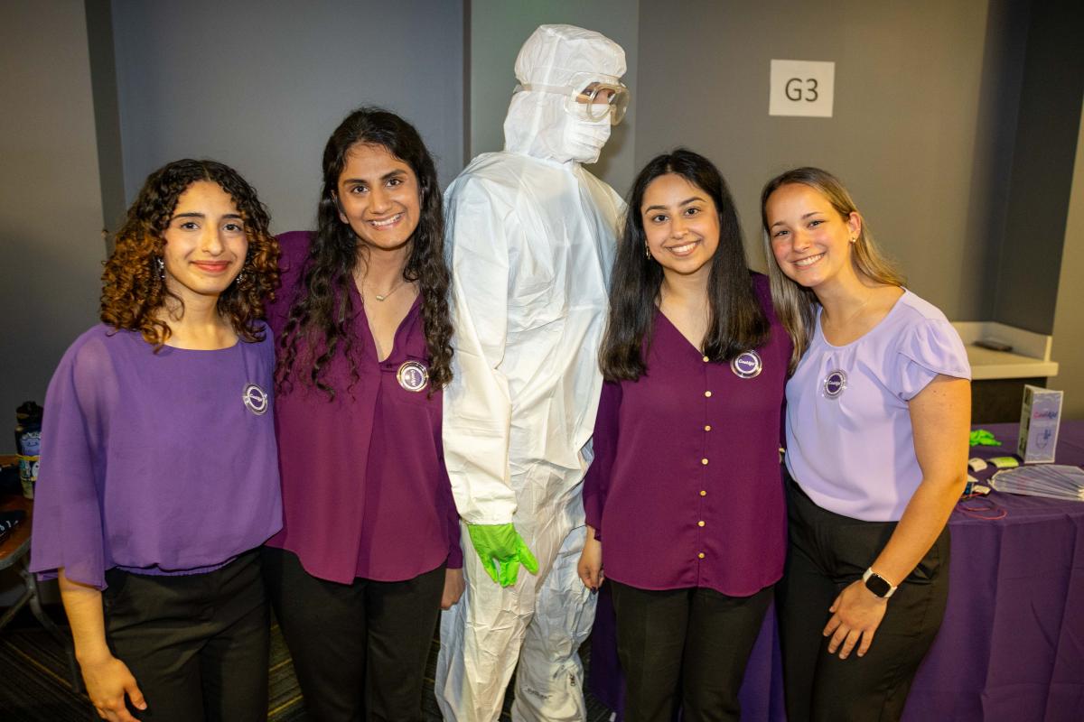 four students standing with a mannequin in a clean room suit