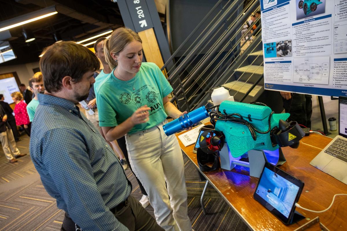 Two people look at an aquatic robot