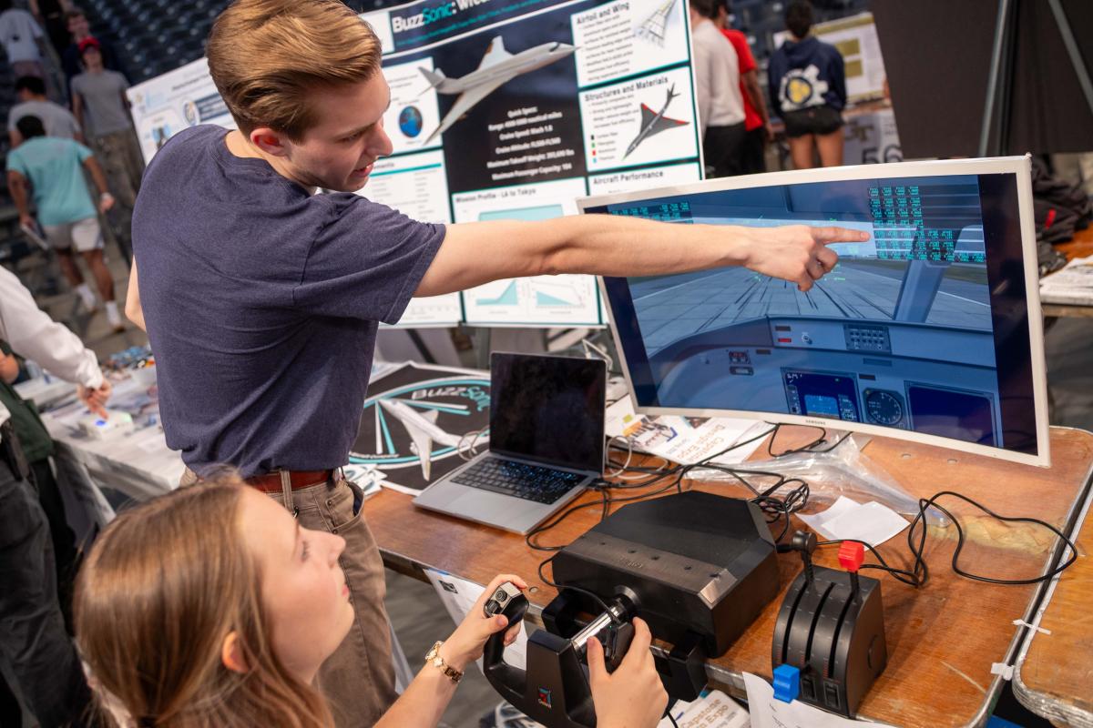 a student controlling a flight simulator and another student pointing at the screen