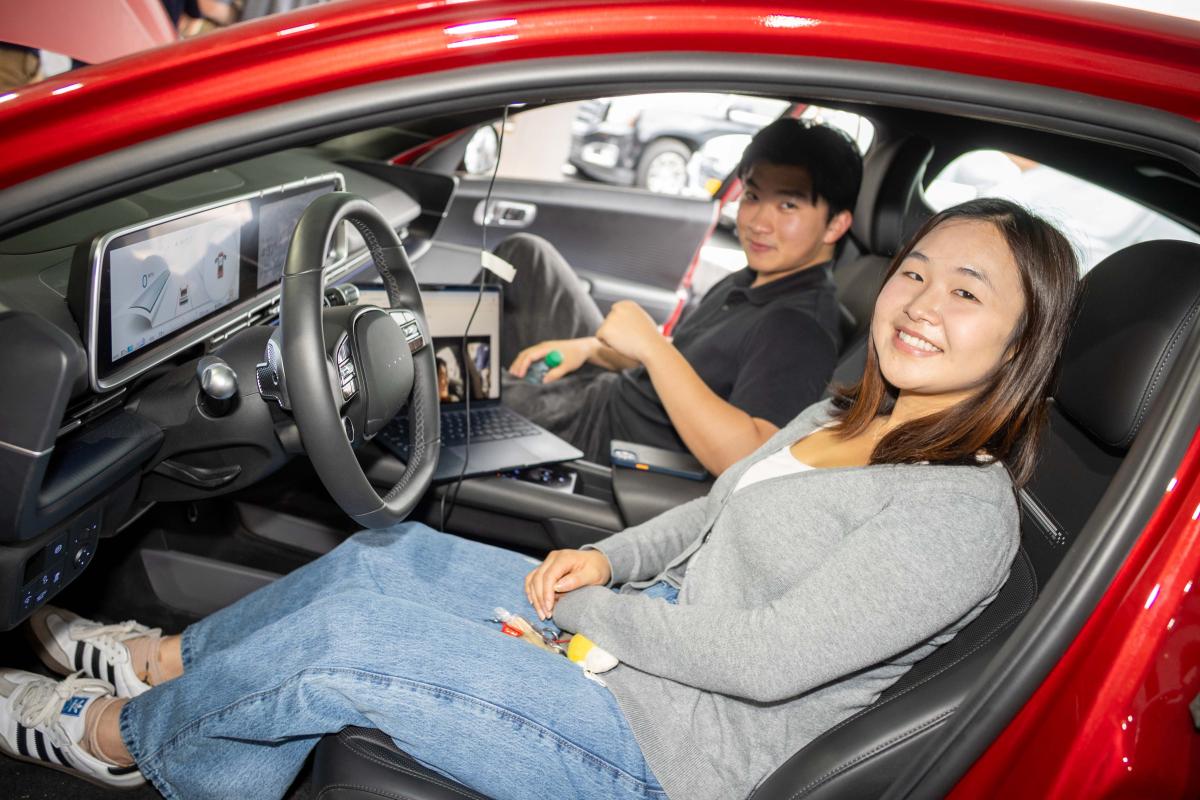 two people sitting in a red car with a new dashboard interface