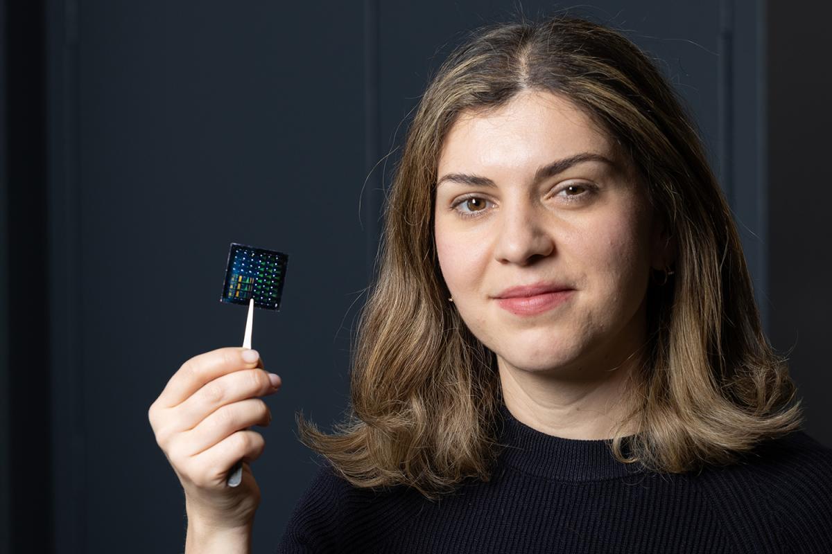 a woman holds up an electronic chip with tweezers