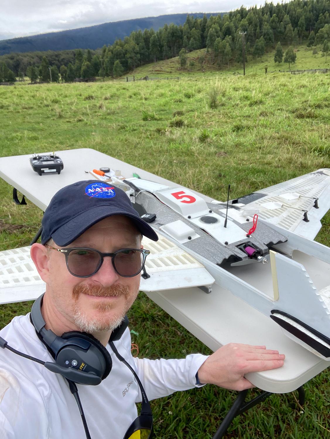 a man stands in a field with a drone