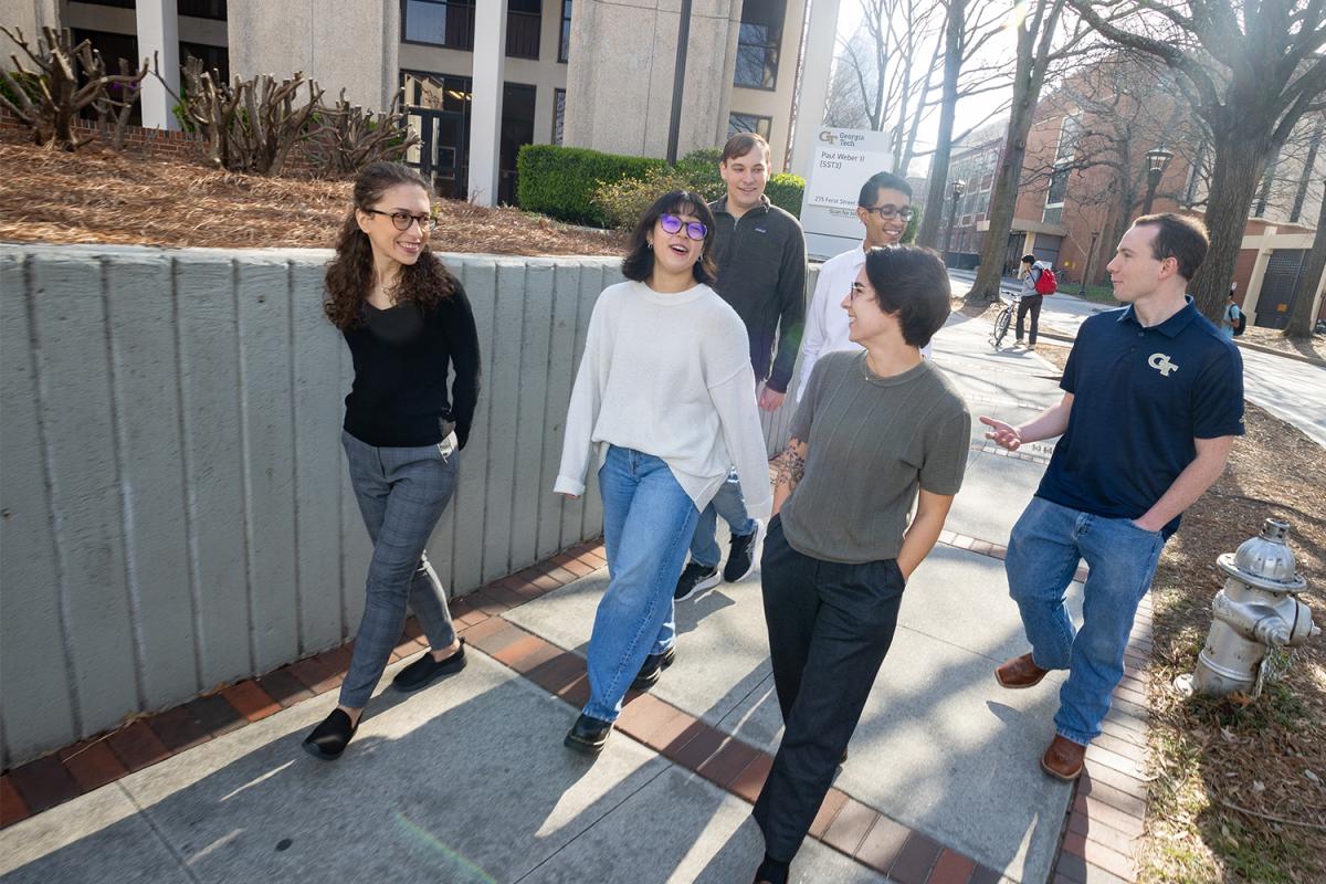 a group of six people walking and talking on campus