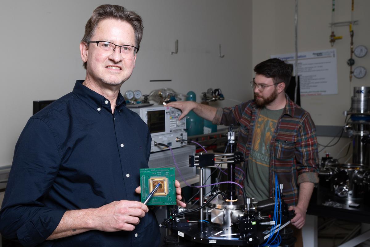 a man in a lab holdig a chip with another person in the background