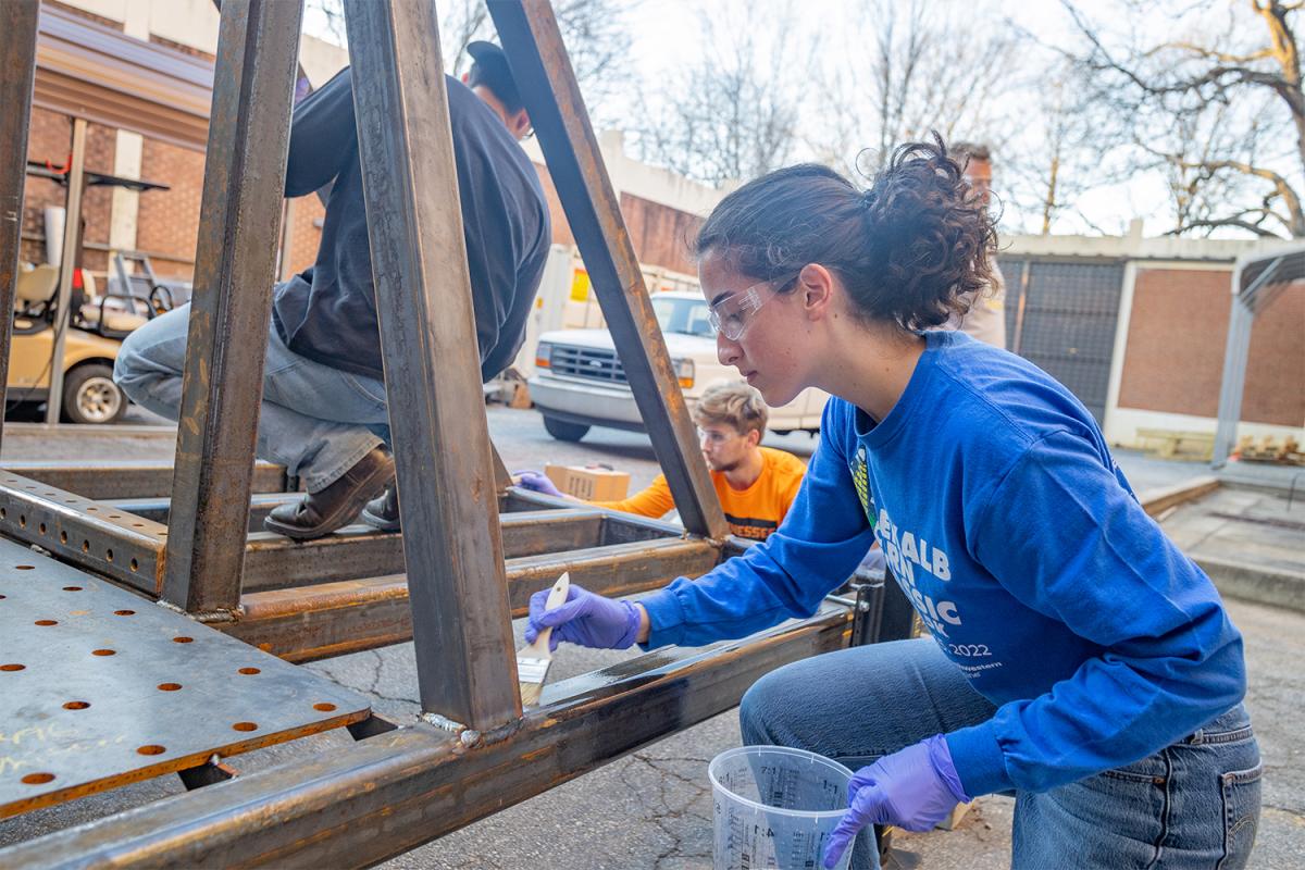 A student paints a steel framework